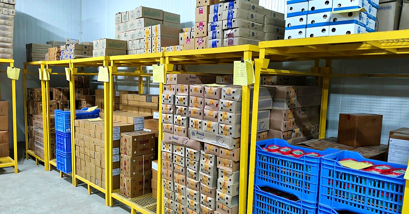 Ice cream and dairy cartons on yellow pallet racking inside the Vilva Fruits cold storage facility in Coimbatore